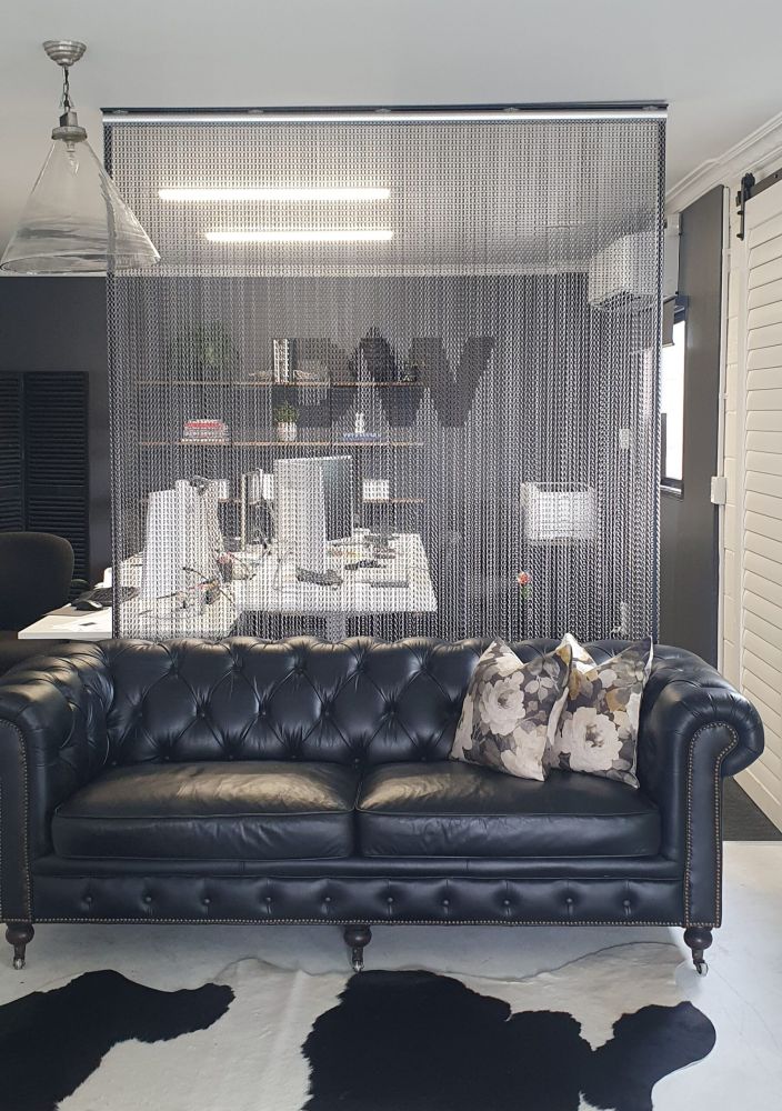 Silver aluminium chain room divider with a company logo in an office reception