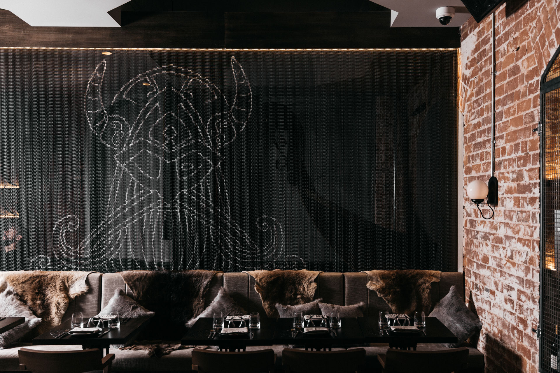 Black aluminium chain wall covering with a white Viking illustration behind restaurant seating