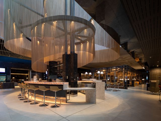 Curved aluminium chain feature suspended above a hospitality bar and lounge area