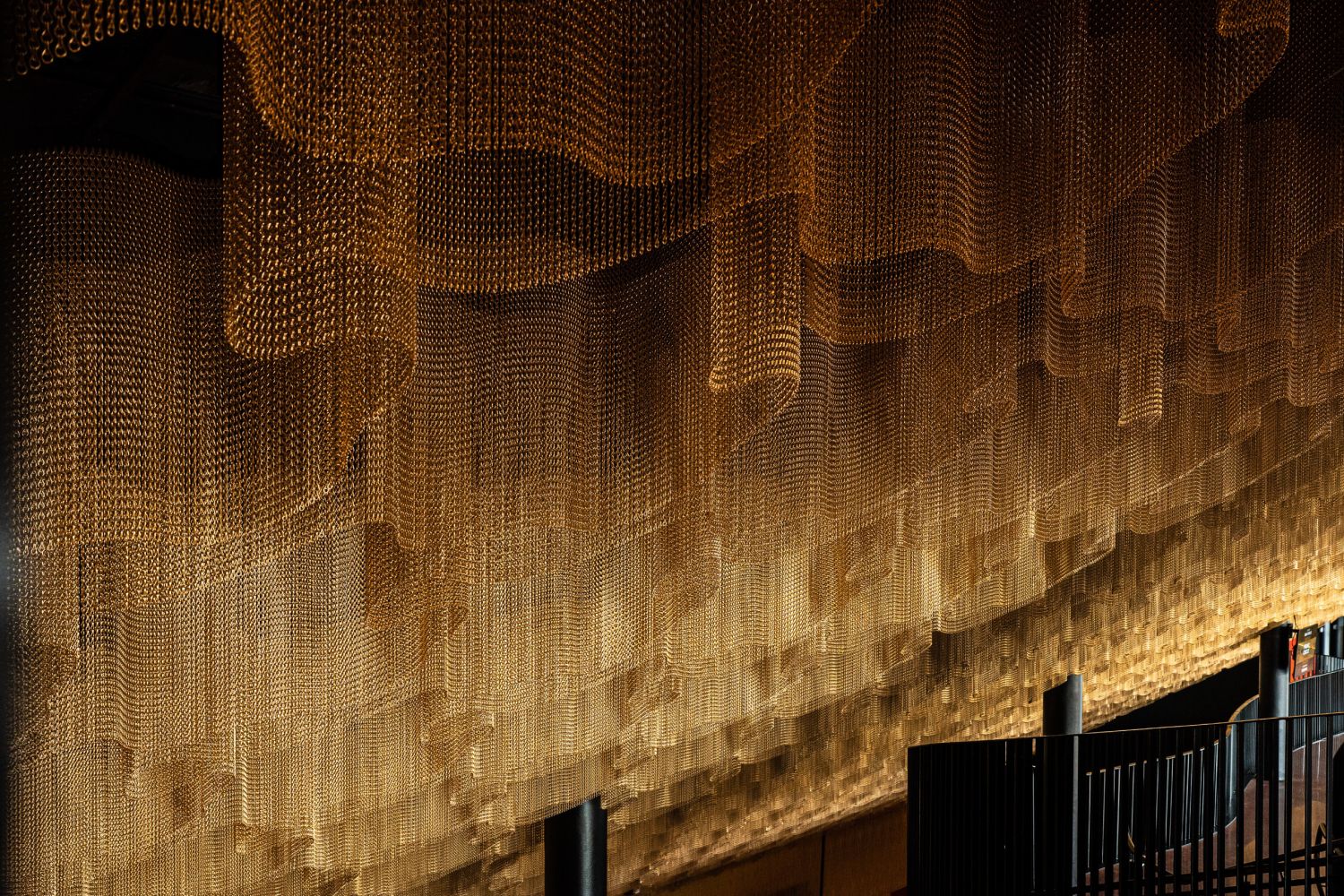 Sculptural gold chain ceiling feature installation with dramatic lighting