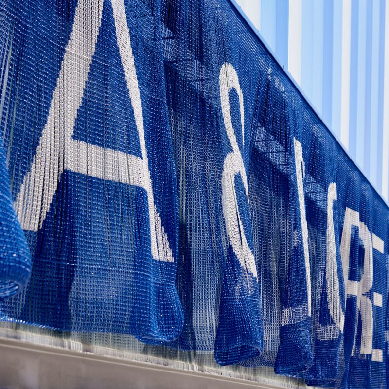 Close-up of blue chain link curtain forming architectural signage lettering on a building facade