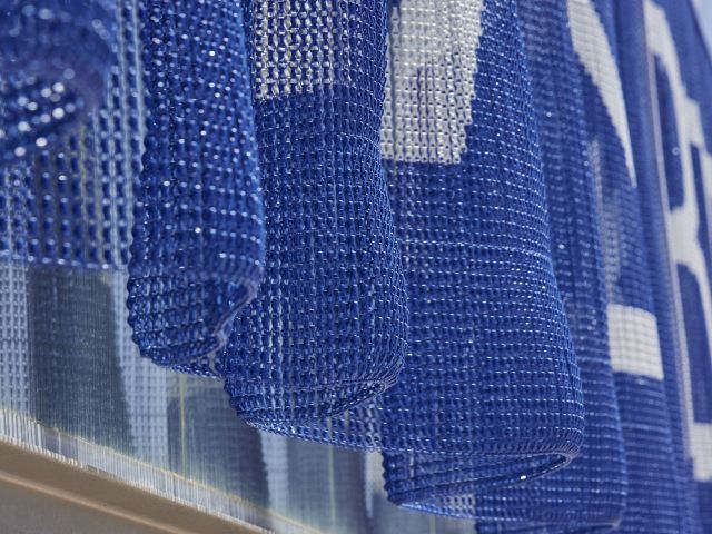 Blue and white patterned aluminium chain curtain with a kinetic mesh effect